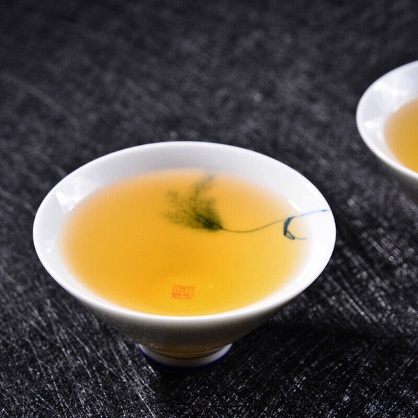 A cup filled with freshly brewed raw Pu-erh tea, displaying a clear, golden-yellow liquor that tastes naturally sweet.